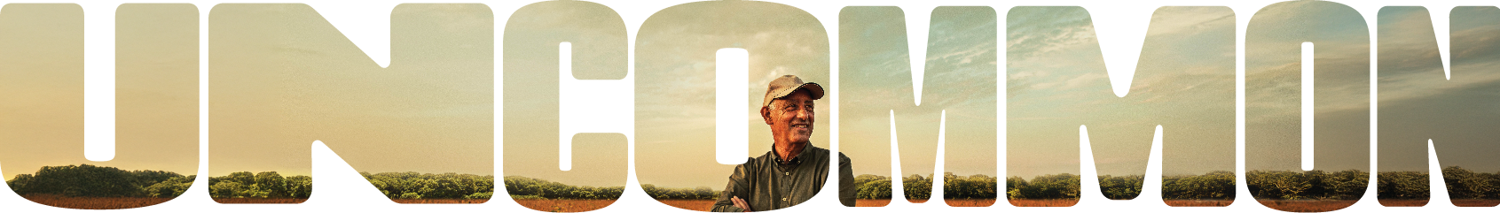 The word 'UNCOMMON' is displayed in large bold letters, each filled with a scenic landscape of a field, trees, and a clear sky. Inside the letter 'O,' a person wearing a hat stands with arms crossed, blending into the natural backdrop.